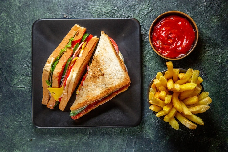 top-view-yummy-ham-sandwich-inside-dark-plate-with-french-fries-ketchup-dark-surface_179666-35672